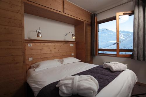 um quarto com uma cama e uma janela com montanhas em Le Chalet du Mont Vallon Spa Resort em Les Menuires