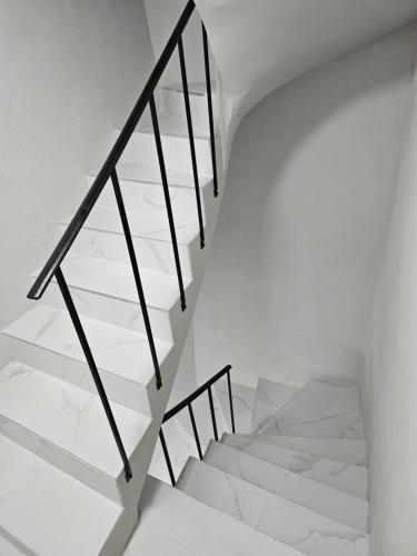 un escalier blanc avec des rampes noires dans une pièce blanche dans l'établissement Appartement moderne et sympa, à Béziers