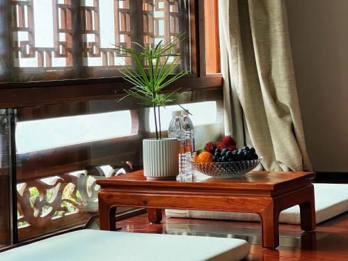 a table with a bowl of fruit and a plant on it at 原乡文苑客栈 in Lijiang