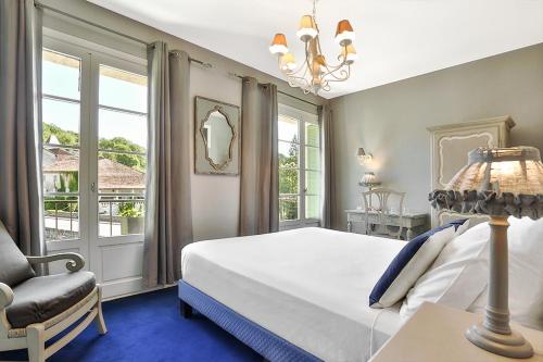 a bedroom with a bed and a chair and windows at Hotel Restaurant Charbonnel in Brantôme