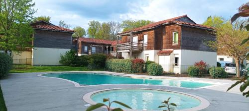 a house with a swimming pool in front of a house at Les Terrasses du Lac piscine A4 in Aureilhan