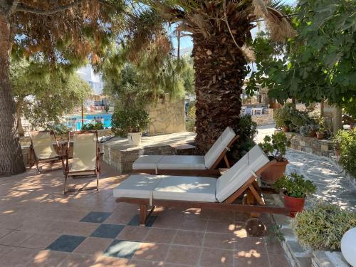 a patio with a white couch and chairs under a tree at Ioanna Apartments in Agios Prokopios