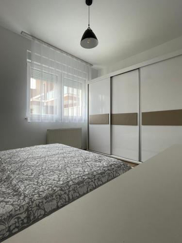 a white bedroom with a bed and a window at Entire Apartment - near the Center in Pristina