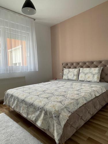 un grande letto in una camera da letto con una grande finestra di Entire Apartment - near the Center a Pristina