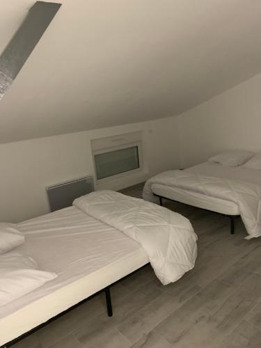 deux lits dans une chambre aux murs blancs dans l'établissement Location vacances, à Muzillac