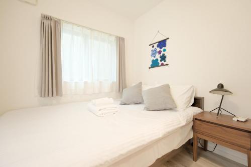 a bedroom with a white bed and a window at Mi-Villa Kami-Ikebukuro in Tokyo