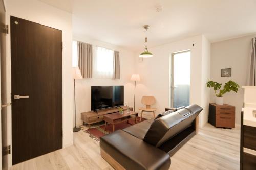 a living room with a leather couch and a television at Mi-Villa Kami-Ikebukuro in Tokyo