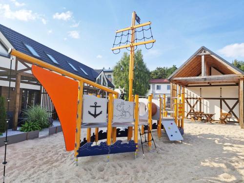 an outdoor playground with an orange and blue slide at Patyki Kamyki in Ustka