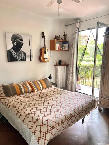 - une chambre avec un lit et une guitare sur le mur dans l'établissement Beau T3 proche mer et aéroport, à Nice
