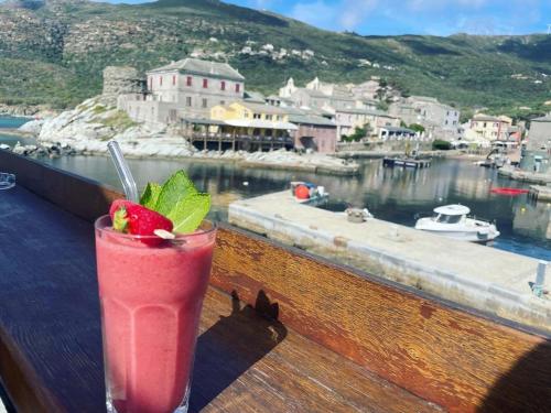 a drink sitting on a railing with a view of a harbor at Hôtel de la jetée in Centuri