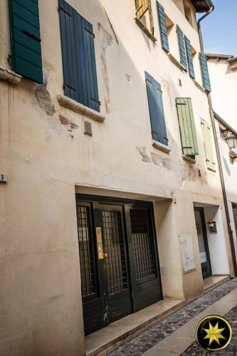 a building with green and blue doors on a street at De Caesar Suite Pordenone in Pordenone