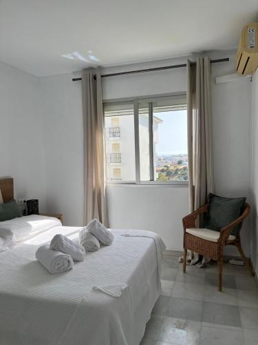 a bedroom with two beds and a chair and a window at Kandy Apartment in Mijas Costa