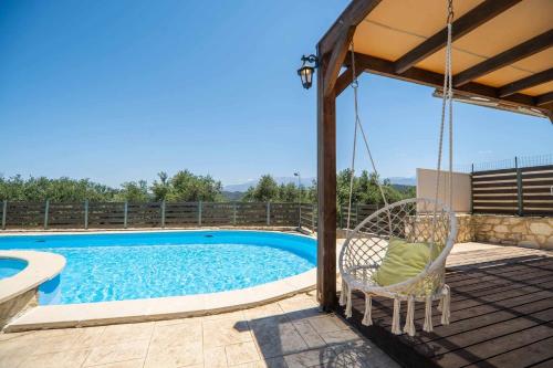a swing on a deck next to a swimming pool at Villa Nimertis in Xirokámbion