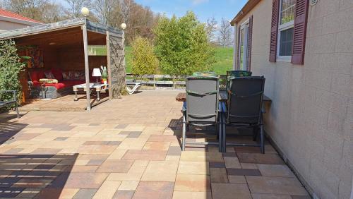 a patio with two chairs on the side of a house at dutchduochalet2 in Heenweg