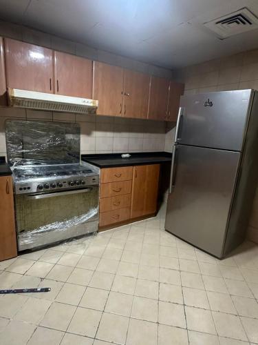 アジュマーンにあるThe Ajman Best Furnished Roomのキッチン(ステンレス製の冷蔵庫、木製キャビネット付)