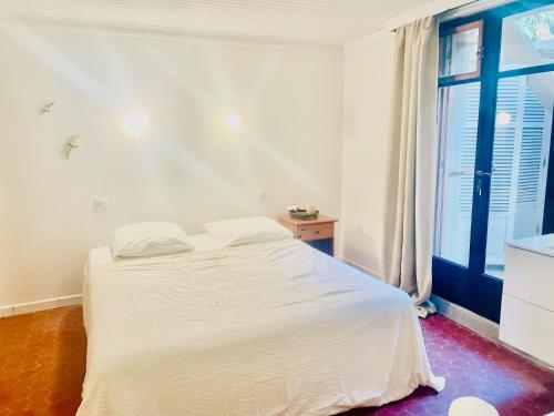 un lit blanc dans une chambre avec une fenêtre dans l'établissement La Maison by Simone, la vrai, à Cannes