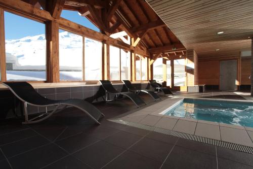 - une piscine avec des chaises dans une pièce avec des montagnes dans l'établissement Le Chalet du Mont Vallon Spa Resort, aux Menuires