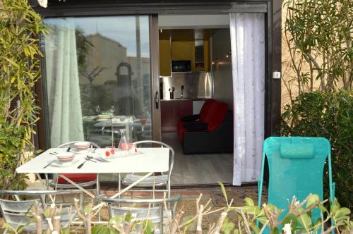 une table blanche et des chaises sur une terrasse dans l'établissement Appart Studio 2 couchages PORT LEUCATE NATURISME PL010-338, à Port-Leucate