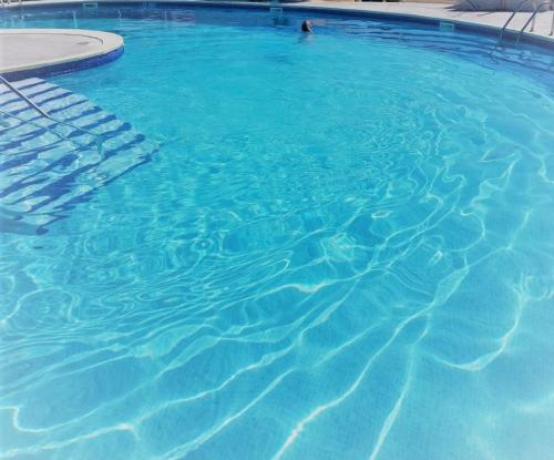 un grand bassin d'eau bleue avec une personne. dans l'établissement Appart Studio 2 couchages PORT LEUCATE NATURISME PL010-338, à Port-Leucate