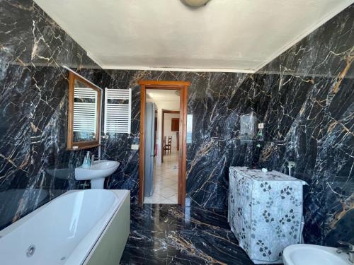 a bathroom with black marble walls and a tub and sink at Appartamento sulla spiaggia Ischia in Ischia