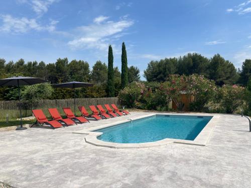une piscine avec des chaises longues et un parasol dans l'établissement Proche Roussillon, La villa rouge Luberon, piscine chauffée, climatisation et vue Luberon, à Gargas