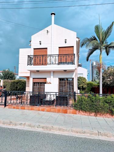 a white building with a balcony and a palm tree at Salty Sunset Holiday Home in Limassol