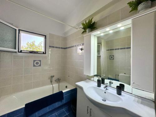 a bathroom with a sink and a tub and a mirror at Villa Serenity Spilia Garden floor in Argostoli