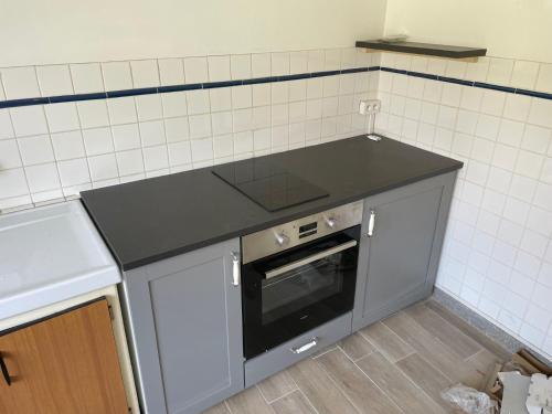 - une cuisine avec un comptoir noir et un four dans l'établissement PEYRISSAC, à Peyrissac