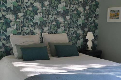 une chambre avec un lit avec un papier peint vert et blanc dans l'établissement 7enGarrigue - Charmant deux pièces avec piscine, à Uzès