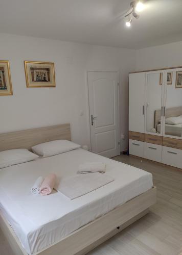 a white bedroom with a large bed and a bathroom at Apartman Mali Tare in Korčula