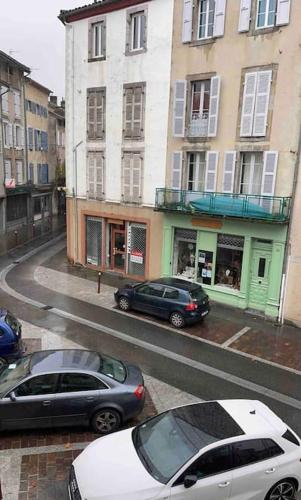 two cars parked on a city street with buildings at Saint-Girons, charmant studio en plein centre in Saint-Girons