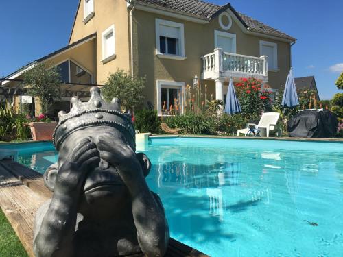 une statue d'une personne portant une couronne à côté d'une piscine dans l'établissement Mille et Une Bulles 51, à Brugny-Vaudancourt