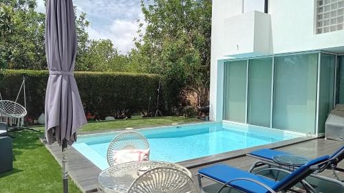 a swimming pool with chairs and an umbrella at Tavira independent suite with Pool at Casa Reflexos in Tavira