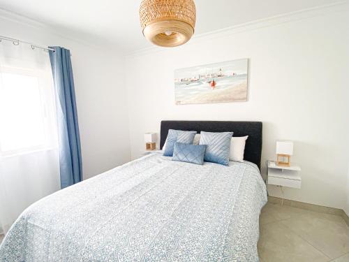 a white bedroom with a bed with blue pillows at Casa Joao in Carvoeiro
