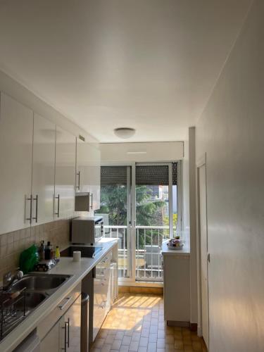 une cuisine avec des placards blancs et une grande fenêtre dans l'établissement Apparemment au cœur de Paris, à Paris