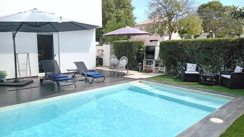 a swimming pool with chairs and an umbrella and a table at Tavira independent suite with Pool at Casa Reflexos in Tavira