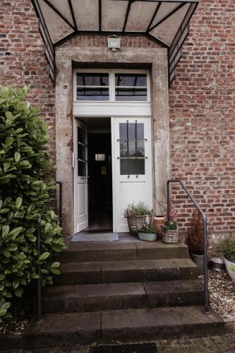 a white door on a brick building with stairs at Im alten Pastorat in Grevenbroich
