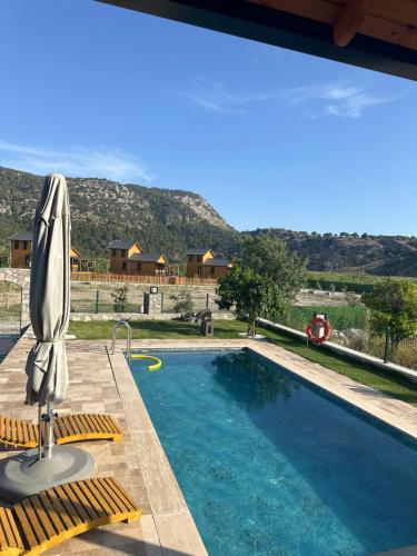 a swimming pool with an umbrella and chairs next to it at Villalakehouse in Dalaman