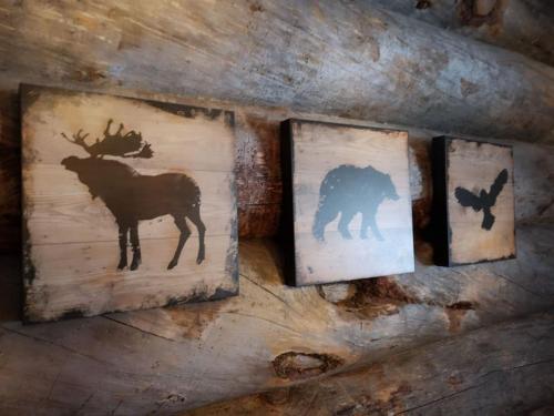 three picture frames with silhouettes of animals on a log at Kelo Villa for 8, with hot tub, by lake Päijänne in Jyväskylä
