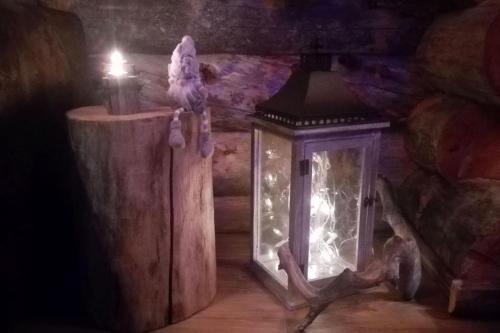 a lantern with a bird sitting on top of a wooden stump at Kelo Villa for 8, with hot tub, by lake Päijänne in Jyväskylä