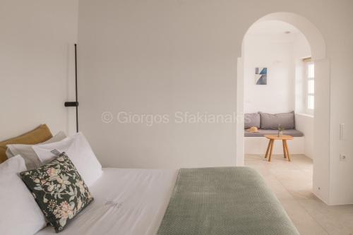 a white bedroom with a bed and a table at Aspaki by Art Maisons in Oia