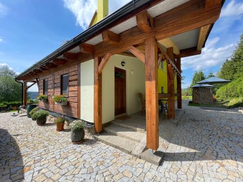 a house with a wooden roof and a patio at Apartmány HÁJOVNA Lipno in Loučovice