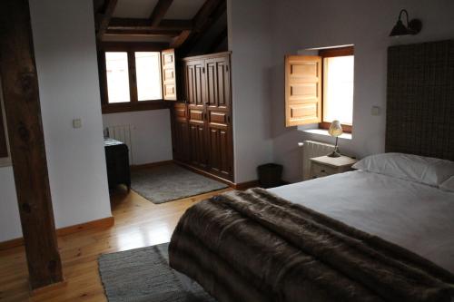 a bedroom with a large bed in a room with windows at La Casona de Castilnovo - Gay Men Only in Valdesaz