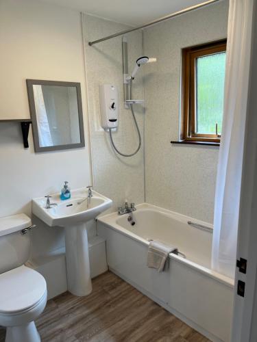 La salle de bains est pourvue d'un lavabo, de toilettes et d'une baignoire. dans l'établissement The Wee Hoose near Loch Ness, private garden, private parking, à Drumnadrochit