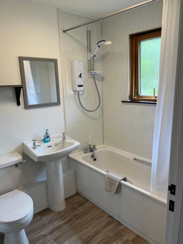 a bathroom with a sink and a toilet and a bath tub at The Wee Hoose near Loch Ness, private garden, private parking in Drumnadrochit