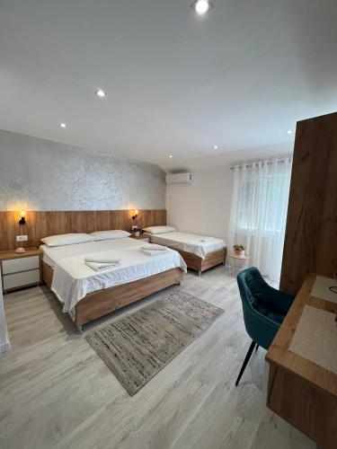 a bedroom with two beds and a blue chair at Apartments Hillside in Ulcinj