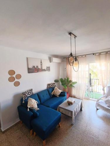 Una sala de estar con un sofá azul y una mesa. en Apartamento Alarve, en Nerja