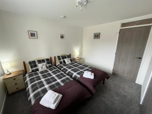 a bedroom with a bed with two towels on it at The Wee Hoose near Loch Ness, private garden, private parking in Drumnadrochit