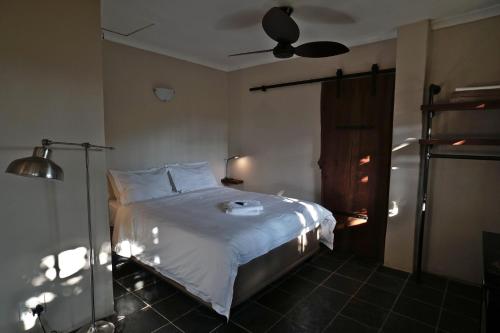 a bedroom with a bed with white sheets and a ceiling fan at Villa La Mercy Guest Suite, No load shedding or water outages in La Mercy
