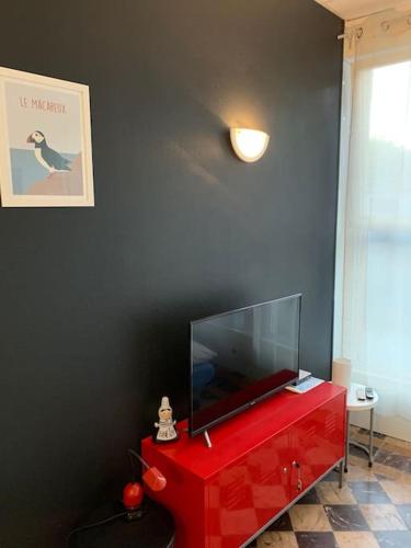 - une commode rouge avec une télévision en haut dans l'établissement Vacances à 50m de la plage et de la mer, à Trégastel